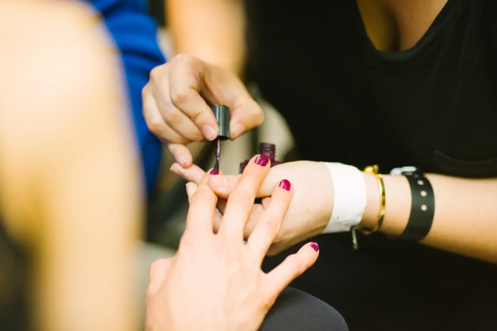 A nail tech painting plum polish onto a client’s nails