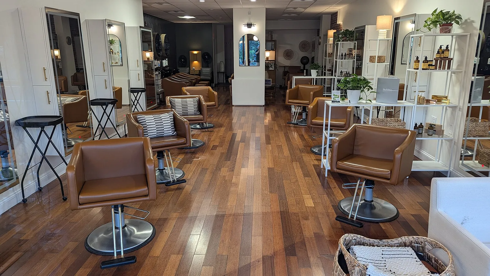 Rows of brown leather chairs facing mirrors on a wood floor